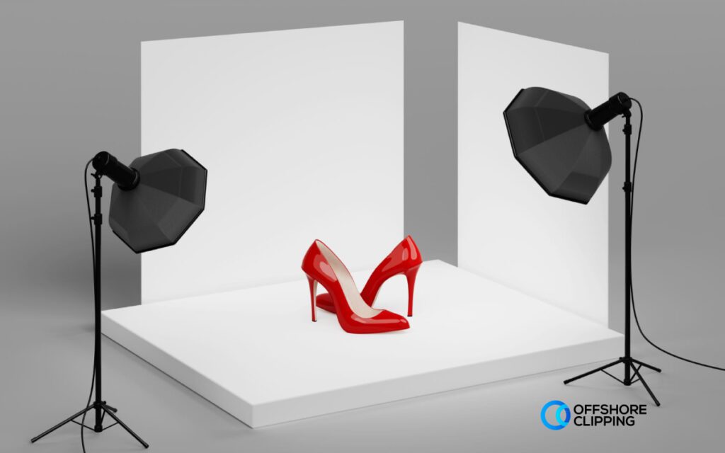 An advertising shot of red high heels on a white platform, lit by two softbox lights against a clean backdrop.