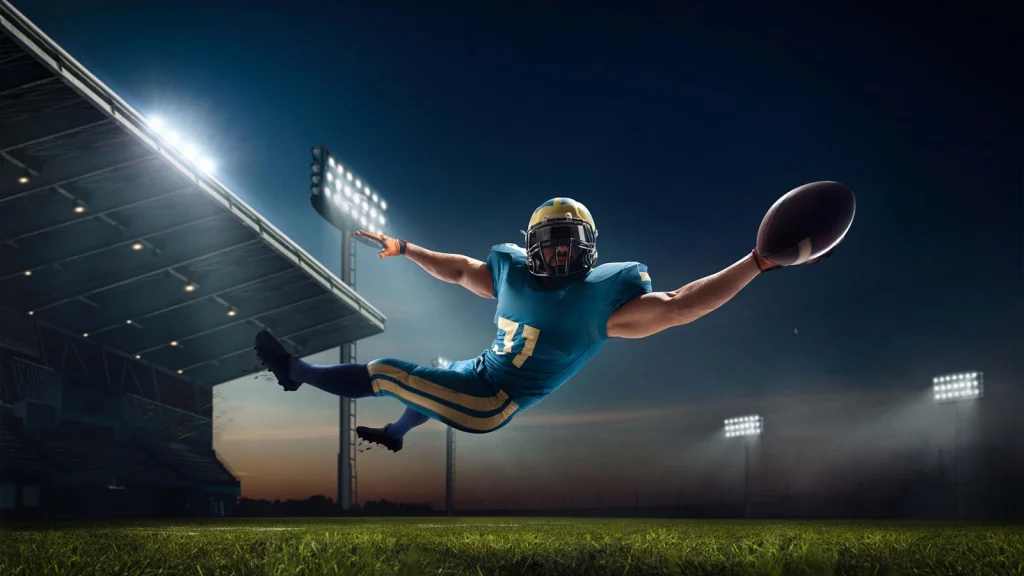 Football player diving mid-air to catch the ball during peak-action sports photography at a stadium