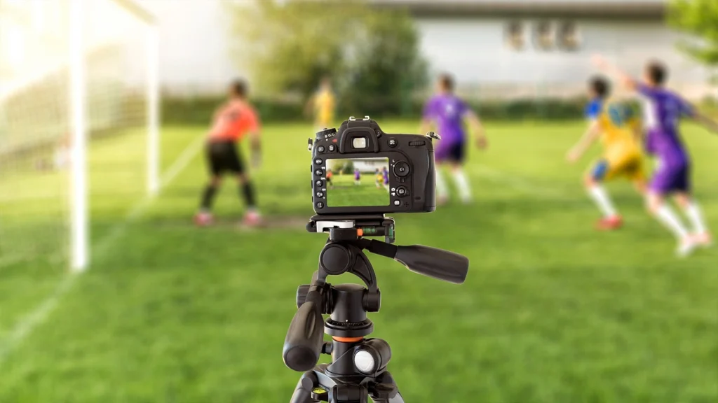 DSLR camera mounted on a tripod capturing a live soccer match, showing essential sports photography equipmen