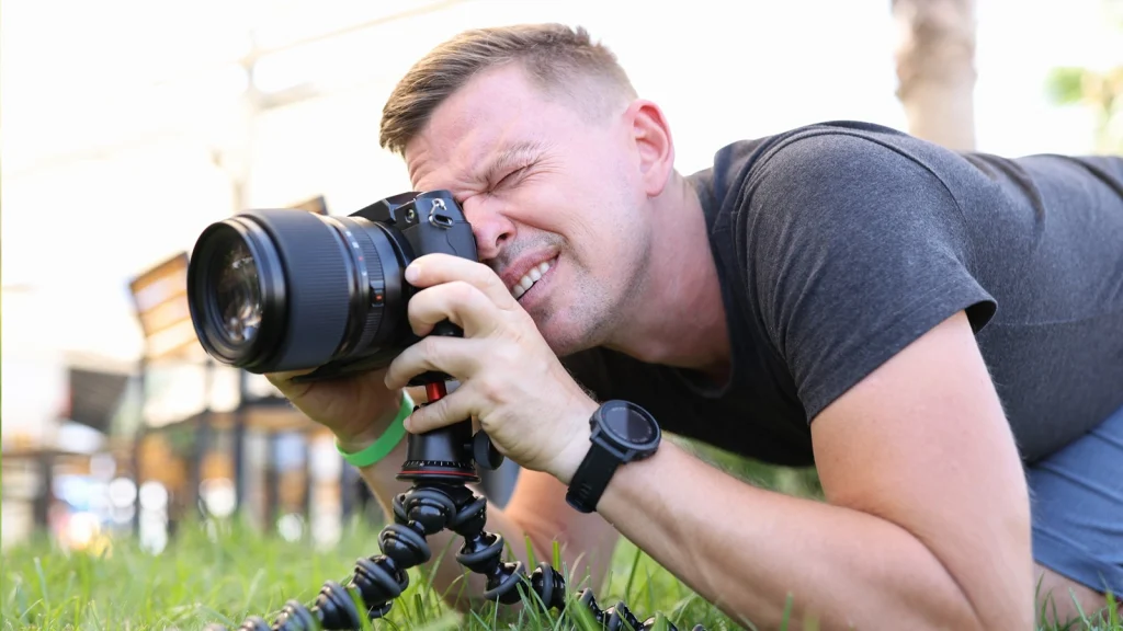 Photographer lying on the ground using a telephoto lens to demonstrate essential sports photography skills