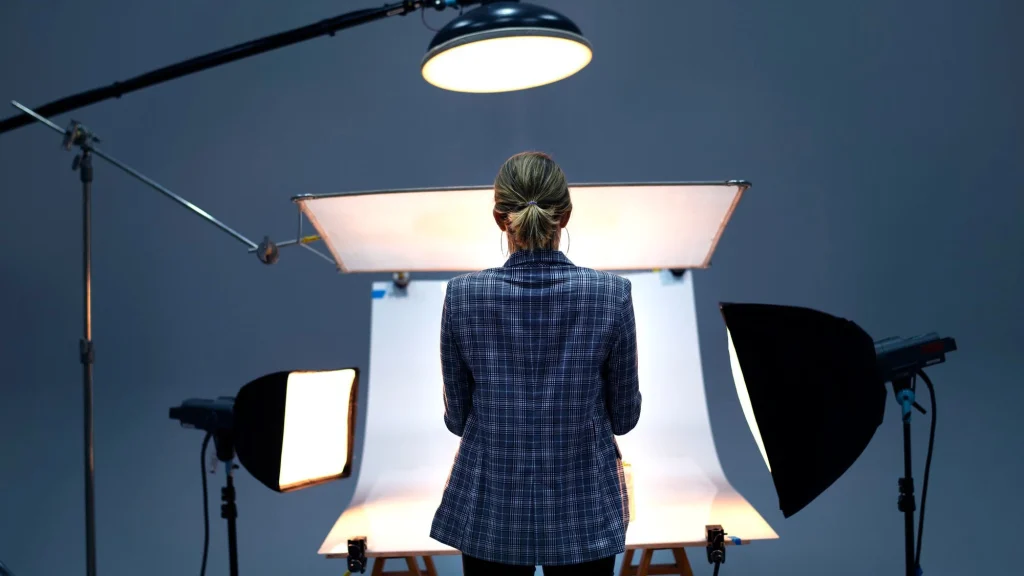 Photographer standing between softbox lights while shooting on a white backdrop