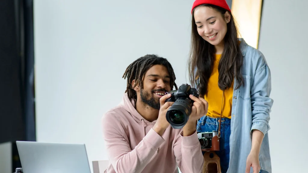 Two photographers reviewing product shots on a DSLR camera screen