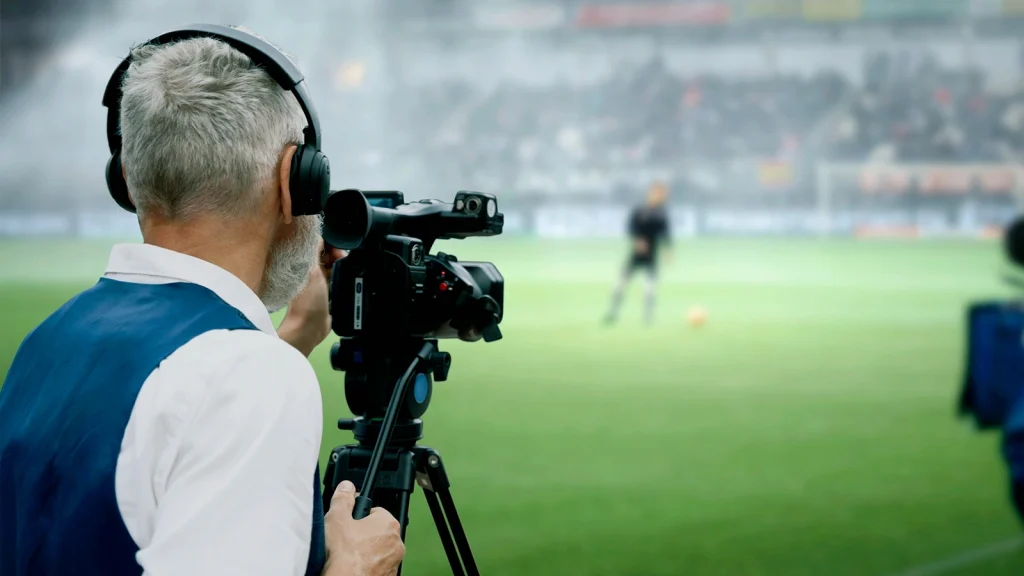 Professional cameraman filming a soccer match from the sidelines, illustrating a career in sports photography