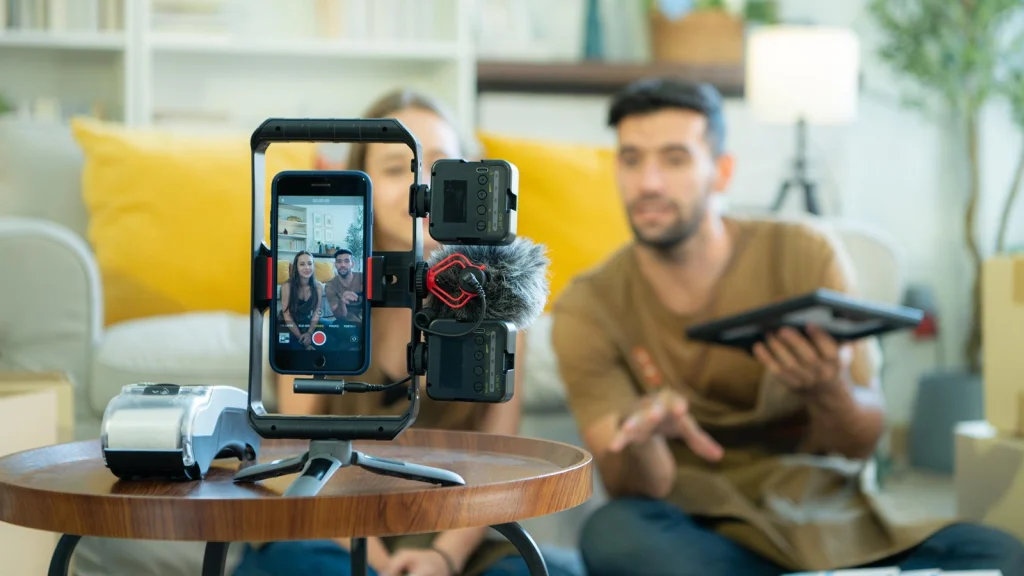 Content creators recording an Instagram Reel with a smartphone, microphone, and camera setup