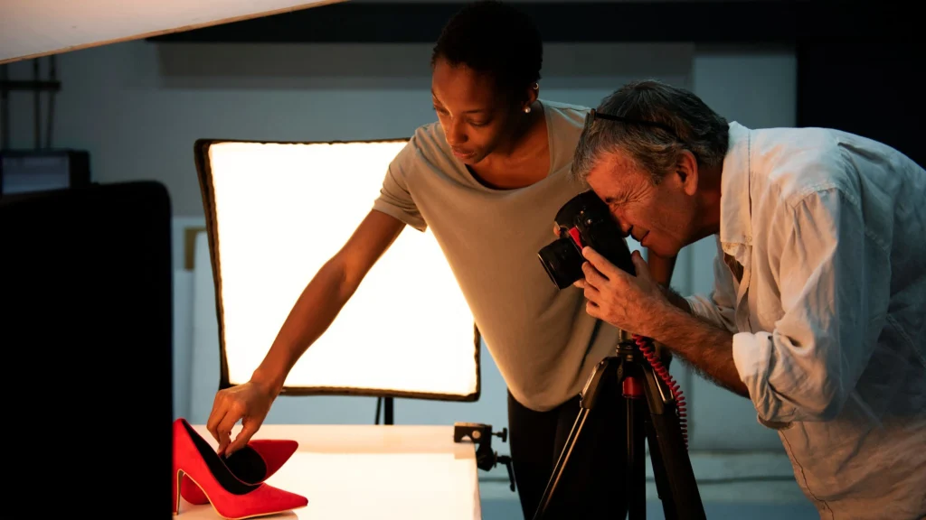 Product photographer and assistant shooting red high heels in a studio setup