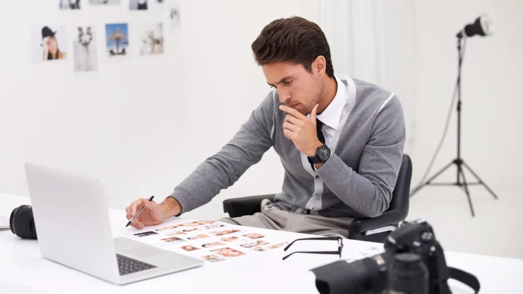 Photographer reviewing photo contact sheets on a laptop before starting the editing process