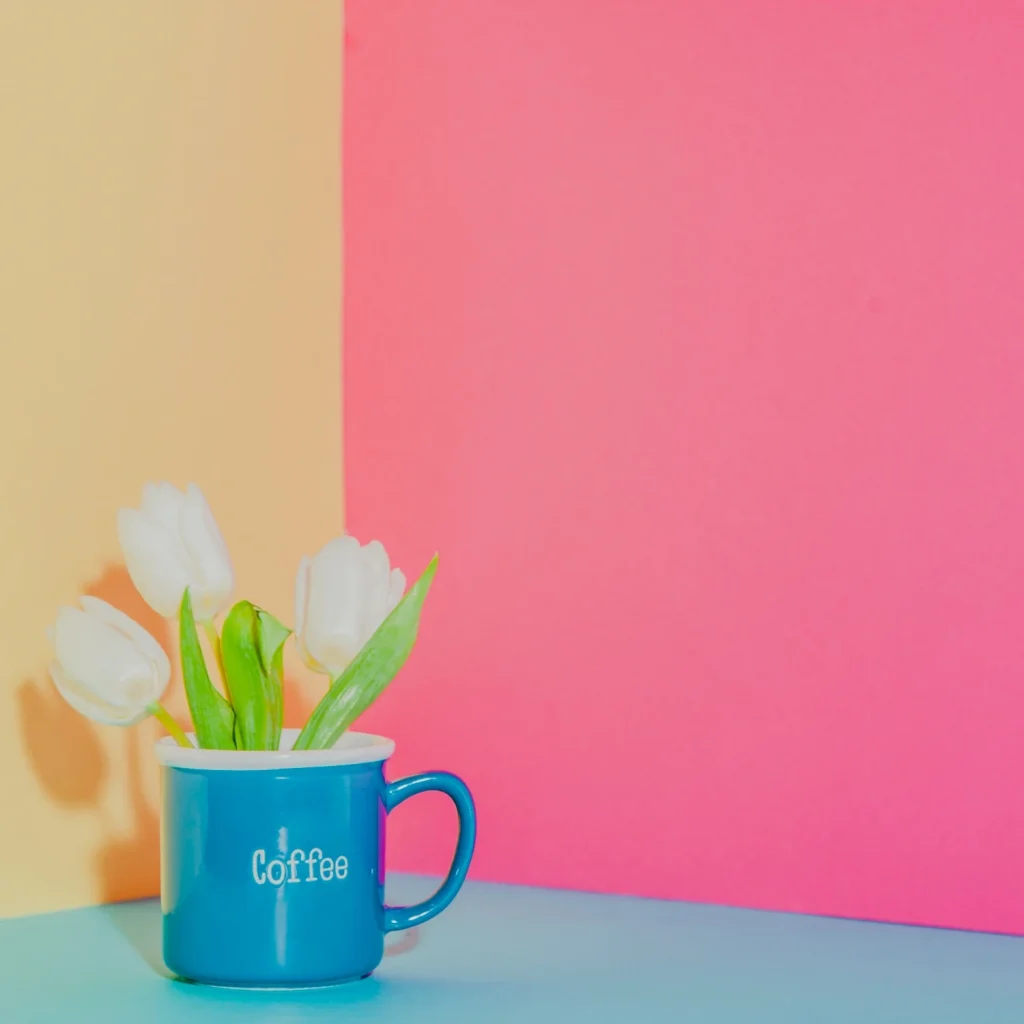 Blue coffee mug with white tulips on a bold color-blocking background for creative product photography.