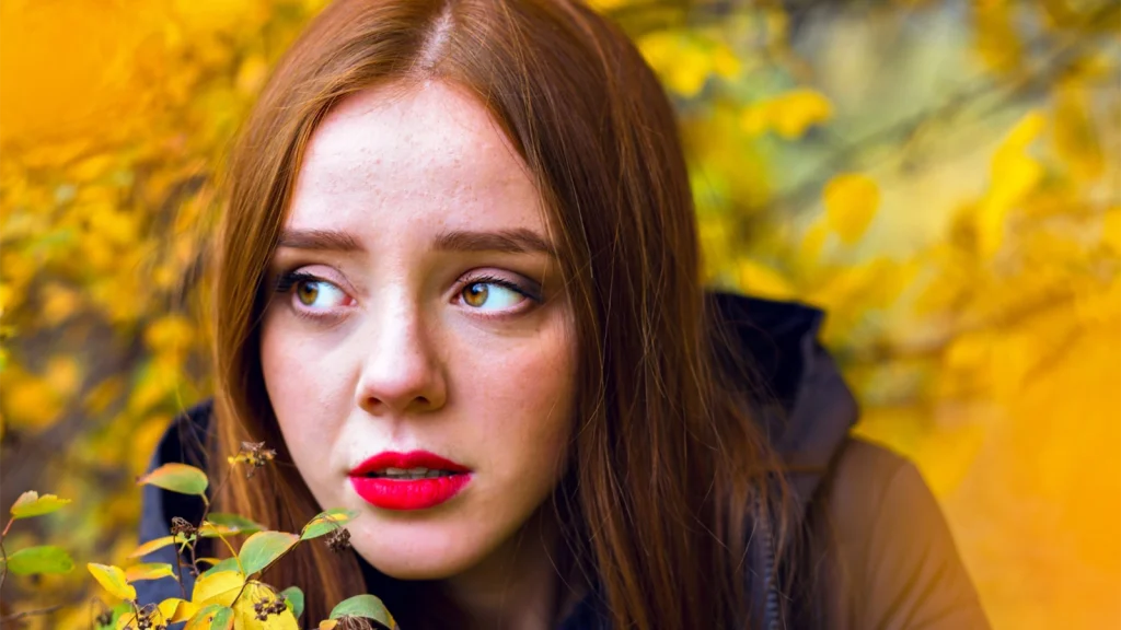 Color graded portrait of a woman with warm golden tones and autumn leaves showing depth and mood