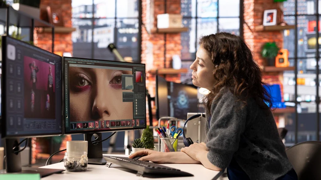 Professional photo editor retouching fashion images on dual computer monitors