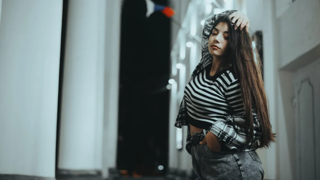 Fashion model posing backstage in a striped outfit during a modern photoshoot