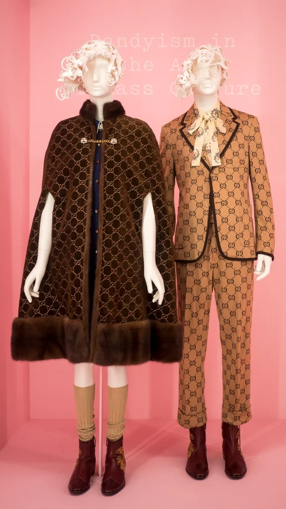 Gucci designer outfits displayed on mannequins against a pink exhibition background
