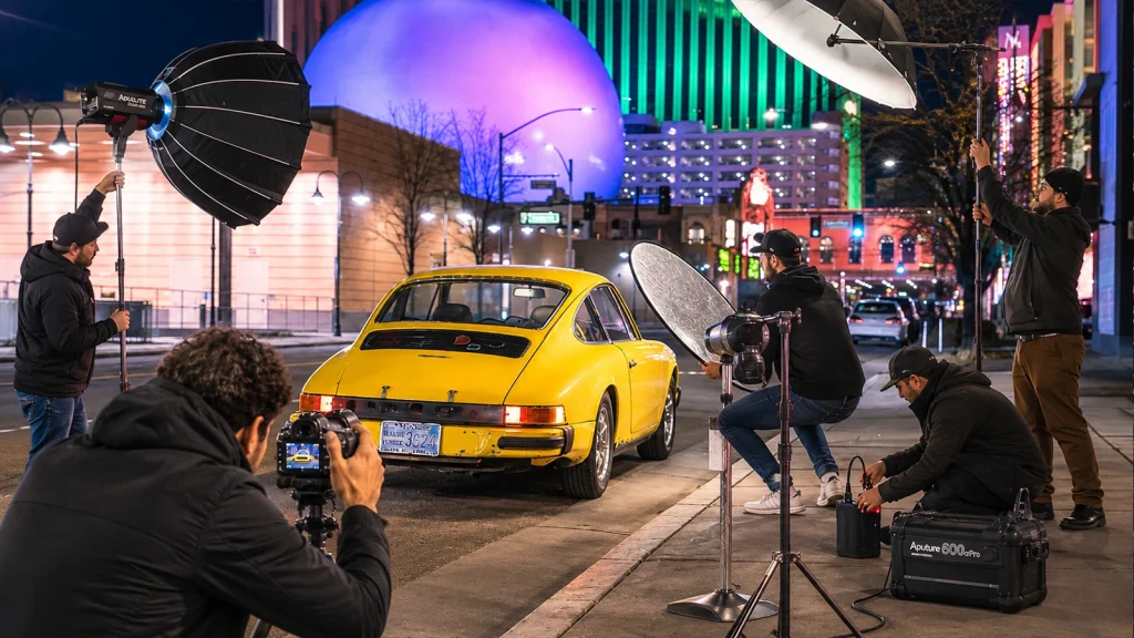 Professional team setting up lights and camera for a night car photography shoot.