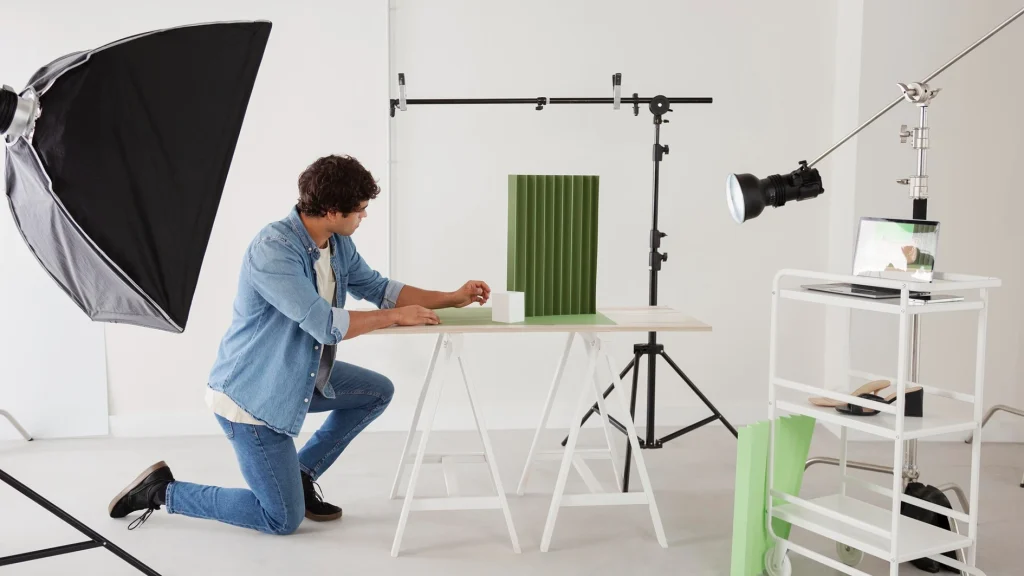 Photographer adjusting light position with a softbox to shape shadows on a product display panel