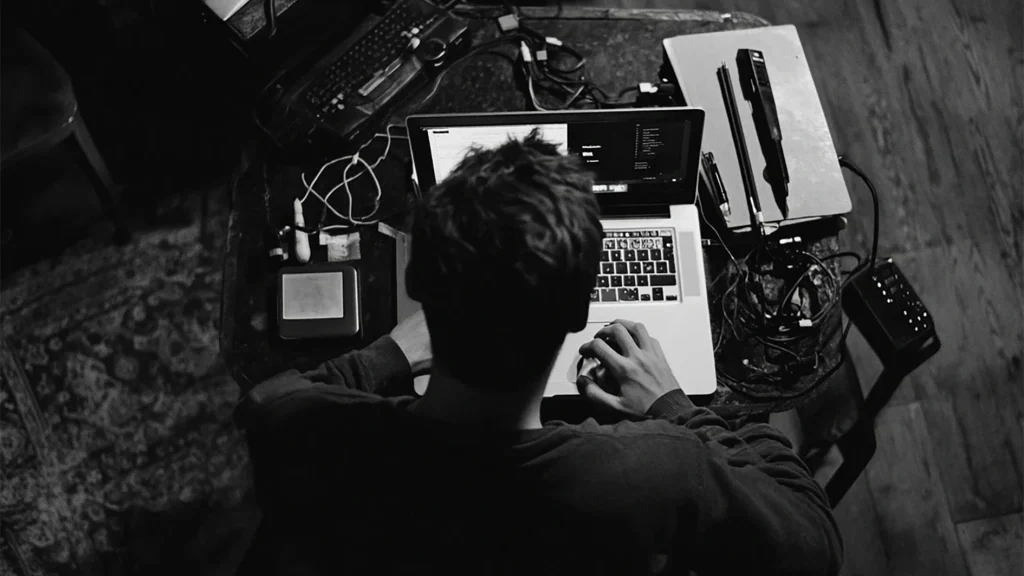 Overhead black and white shot of a photo editor retouching fashion product images on a laptop