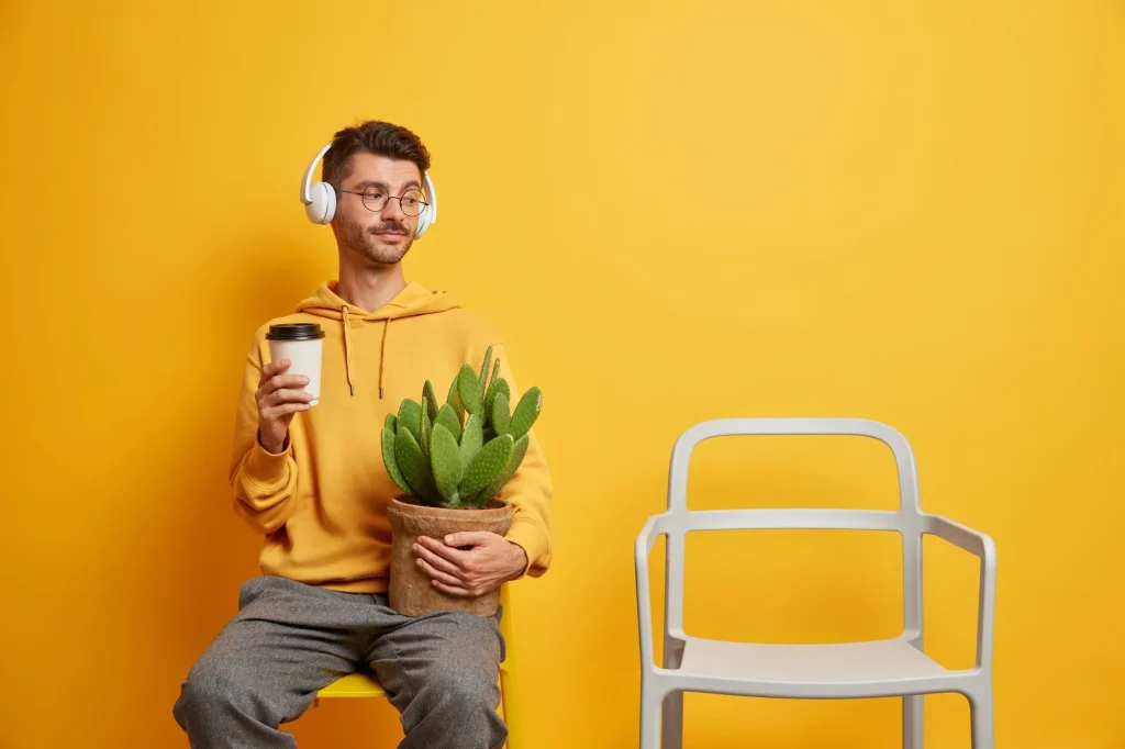 Man holding a coffee cup and cactus plant on a yellow background, showing lifestyle photography across industries