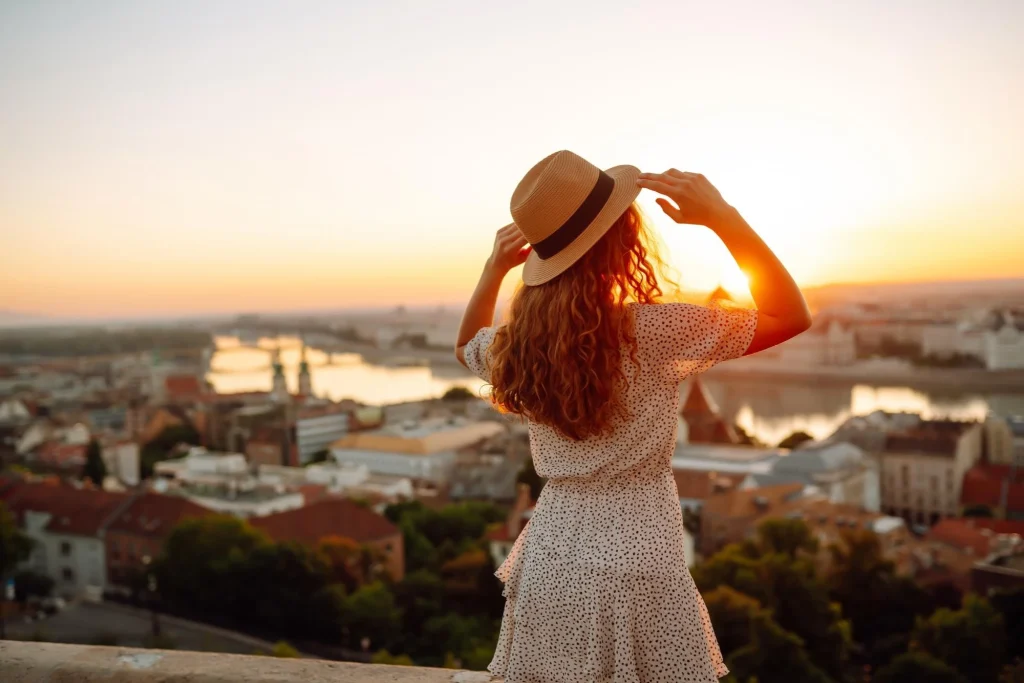 Woman in a straw hat overlooking a city skyline at sunset, reflecting 2026 lifestyle product photography trends