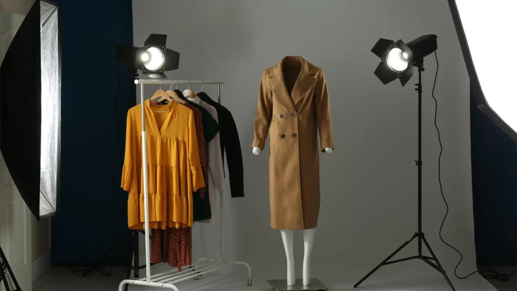 Ghost mannequin technique used to photograph a camel coat beside a clothing rack in a studio