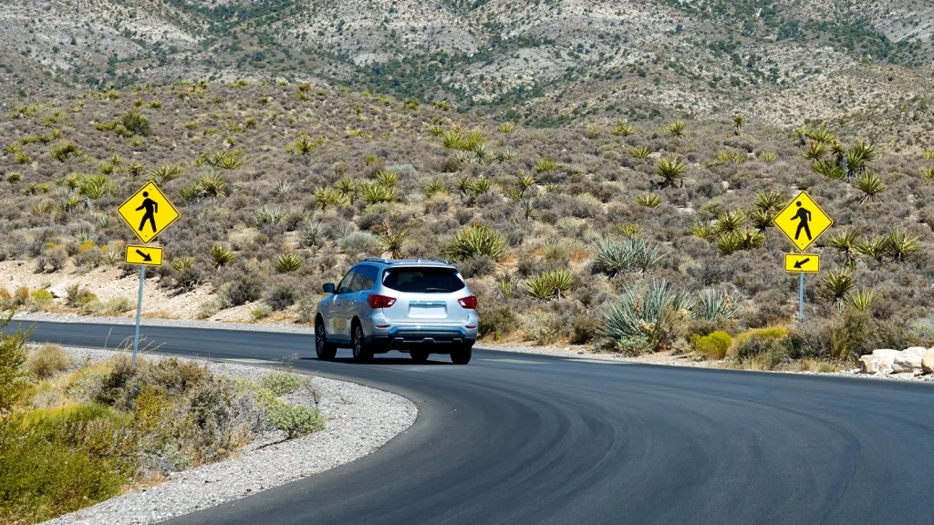 SUV photographed on a coastal highway with mountain and ocean scenery