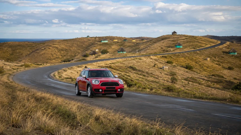 Red car photographed on a winding country road surrounded by open countryside