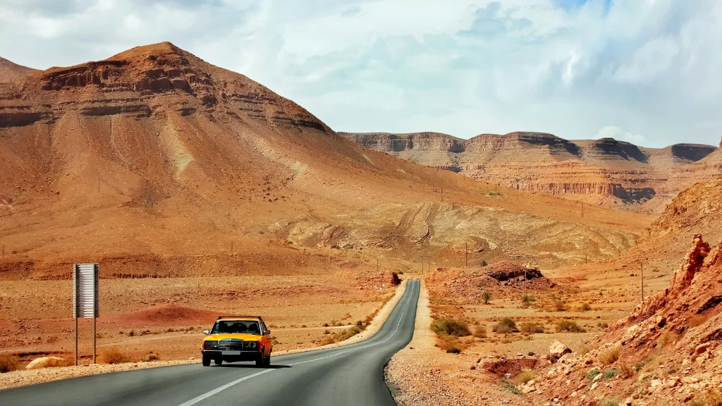 Car photography on a desert road surrounded by open mountain landscapes