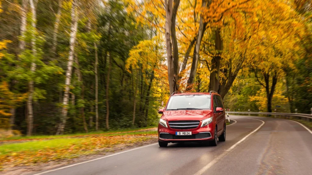 Car photography on a winding forest road with autumn foliage