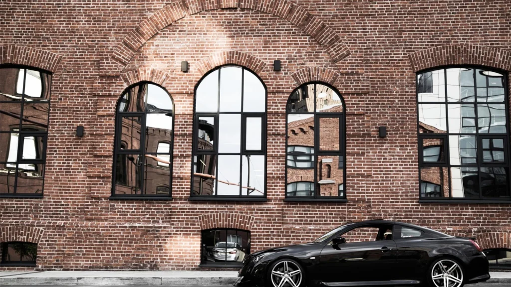 Black sports car photographed against an old brick building for car photography