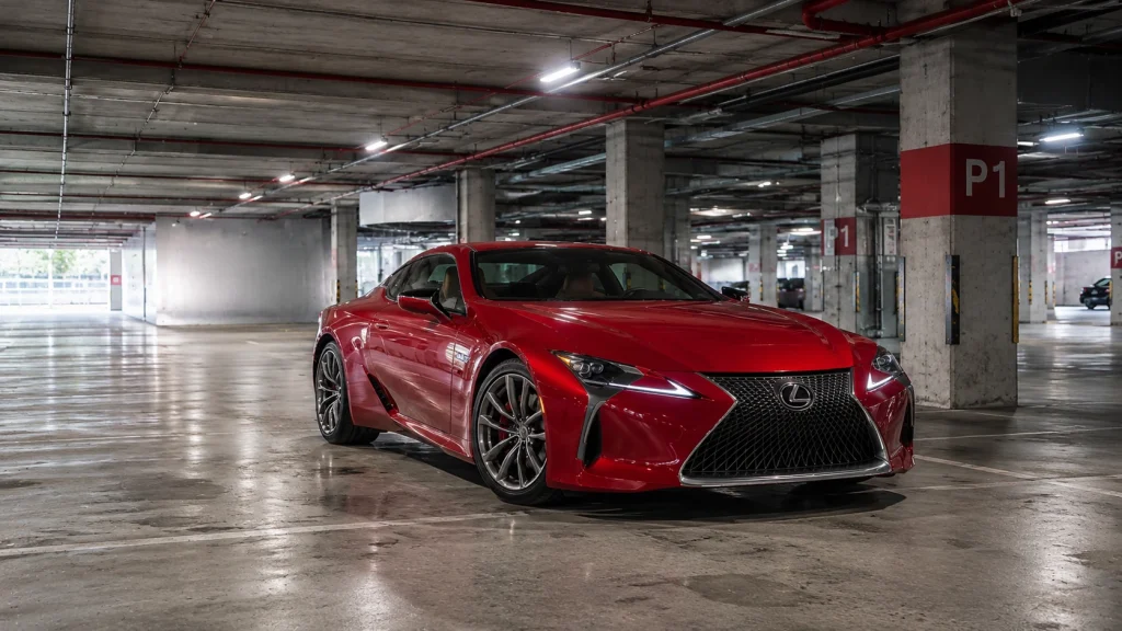 Car photography in an underground parking garage with dramatic lighting and repeating concrete columns.