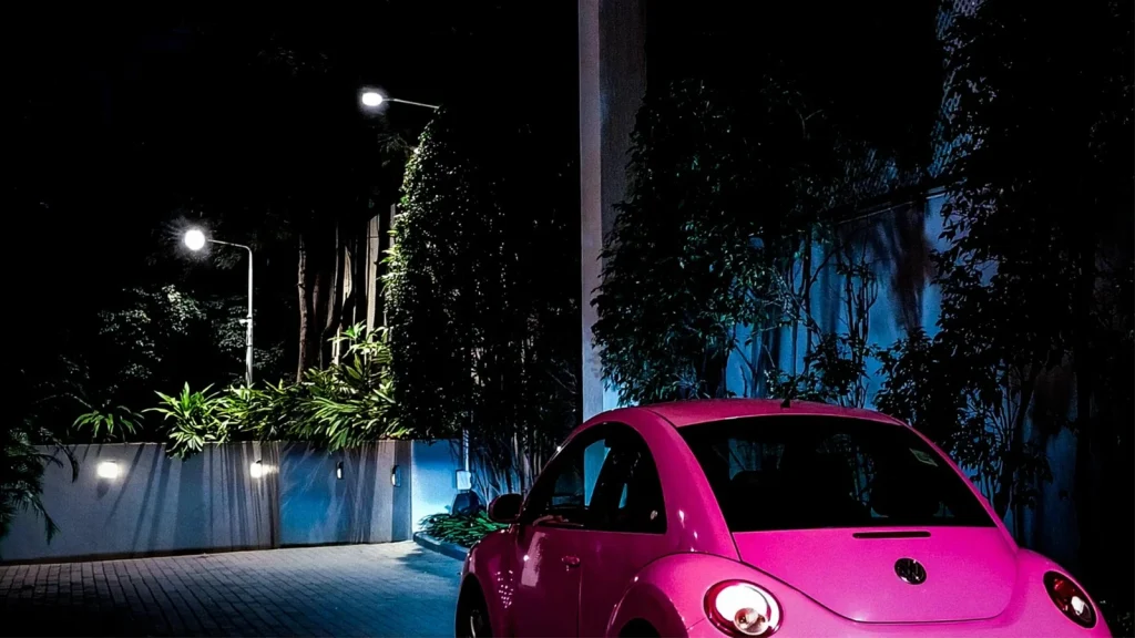 Pink car photographed at night with dramatic artificial lighting
