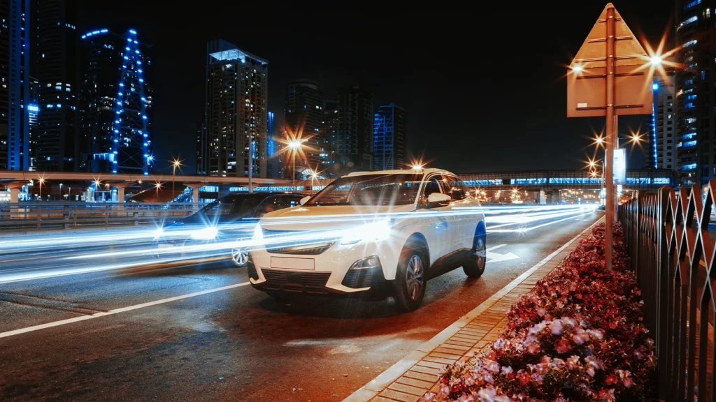 White car photographed on a neon-lit city street at night