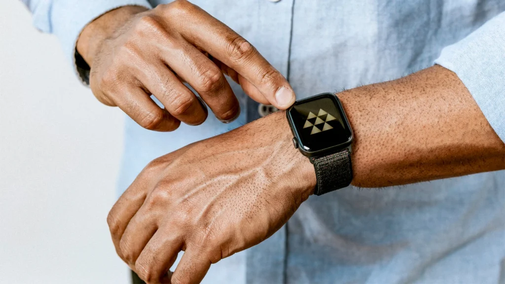 Man adjusting a black smartwatch with digital display on his wrist against a light background