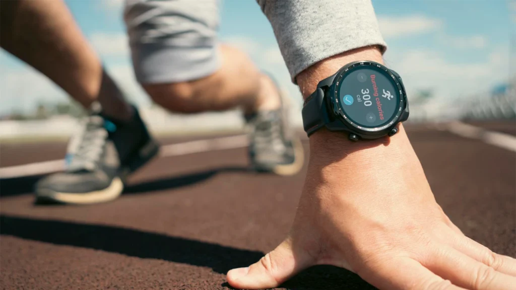 Runner checking a black sports smartwatch displaying calories burned during outdoor exercise