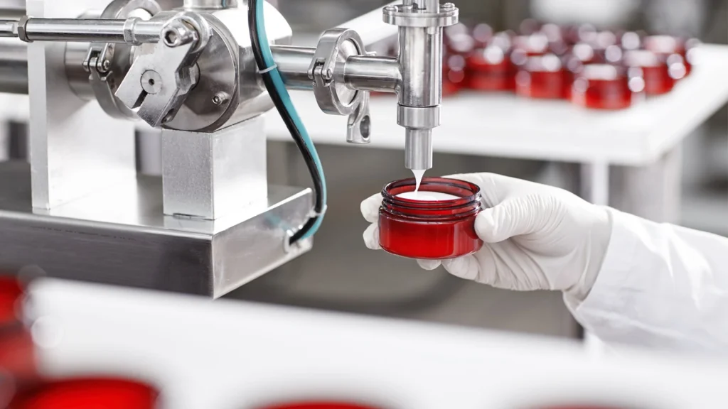 Pharmaceutical product photography showing an automatic filling machine dispensing liquid into a red container