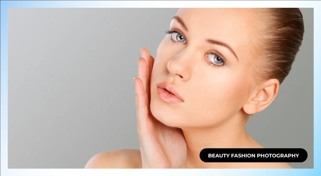 Close-up of a woman with hair pulled back and her hand on her cheek against a gray background, beauty fashion photography